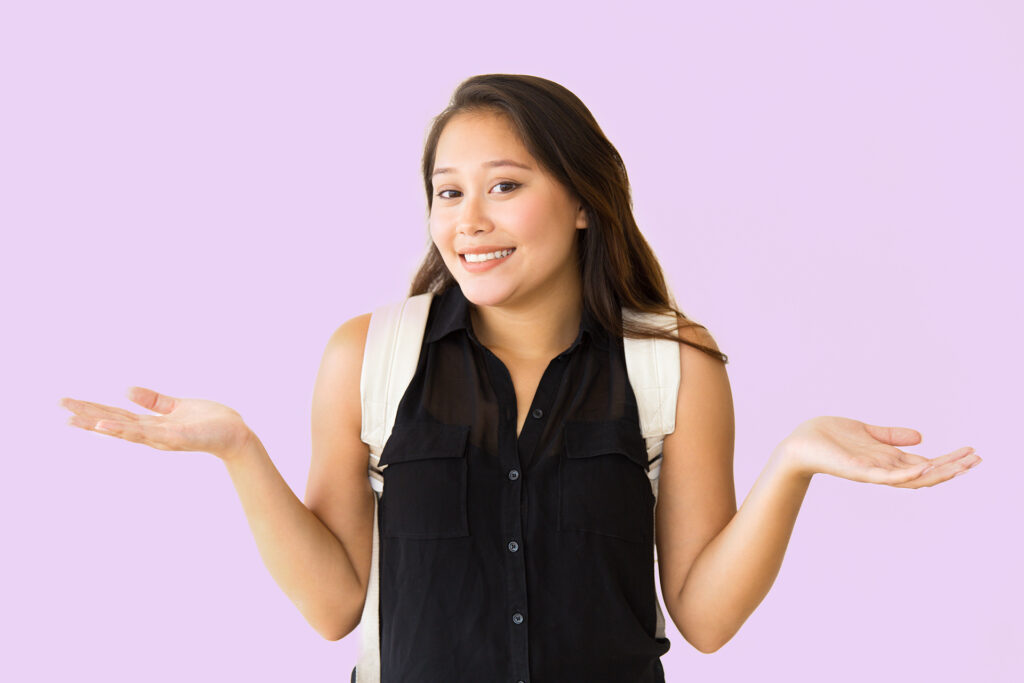 Positive confused teenage student girl shrugging shoulders